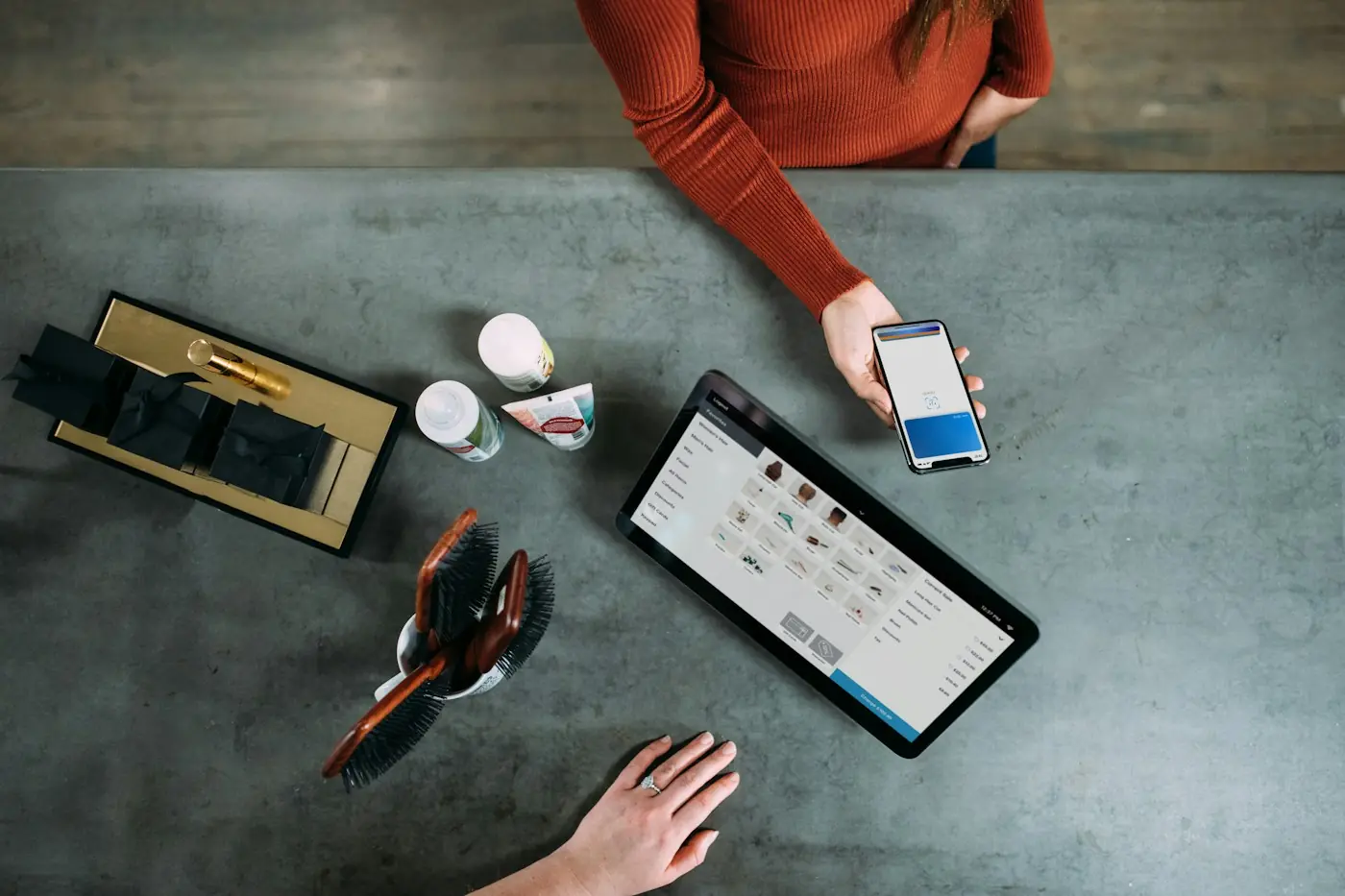 Balcão com tablet exibindo um sistema de vendas e um cliente pagando pelo celular